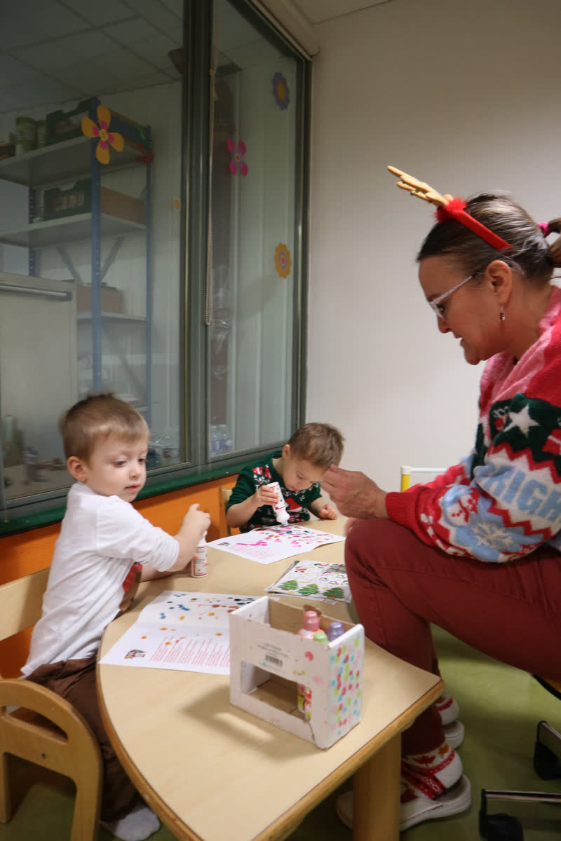Une professionnelle fait une activité avec deux enfants autour d'une petite table