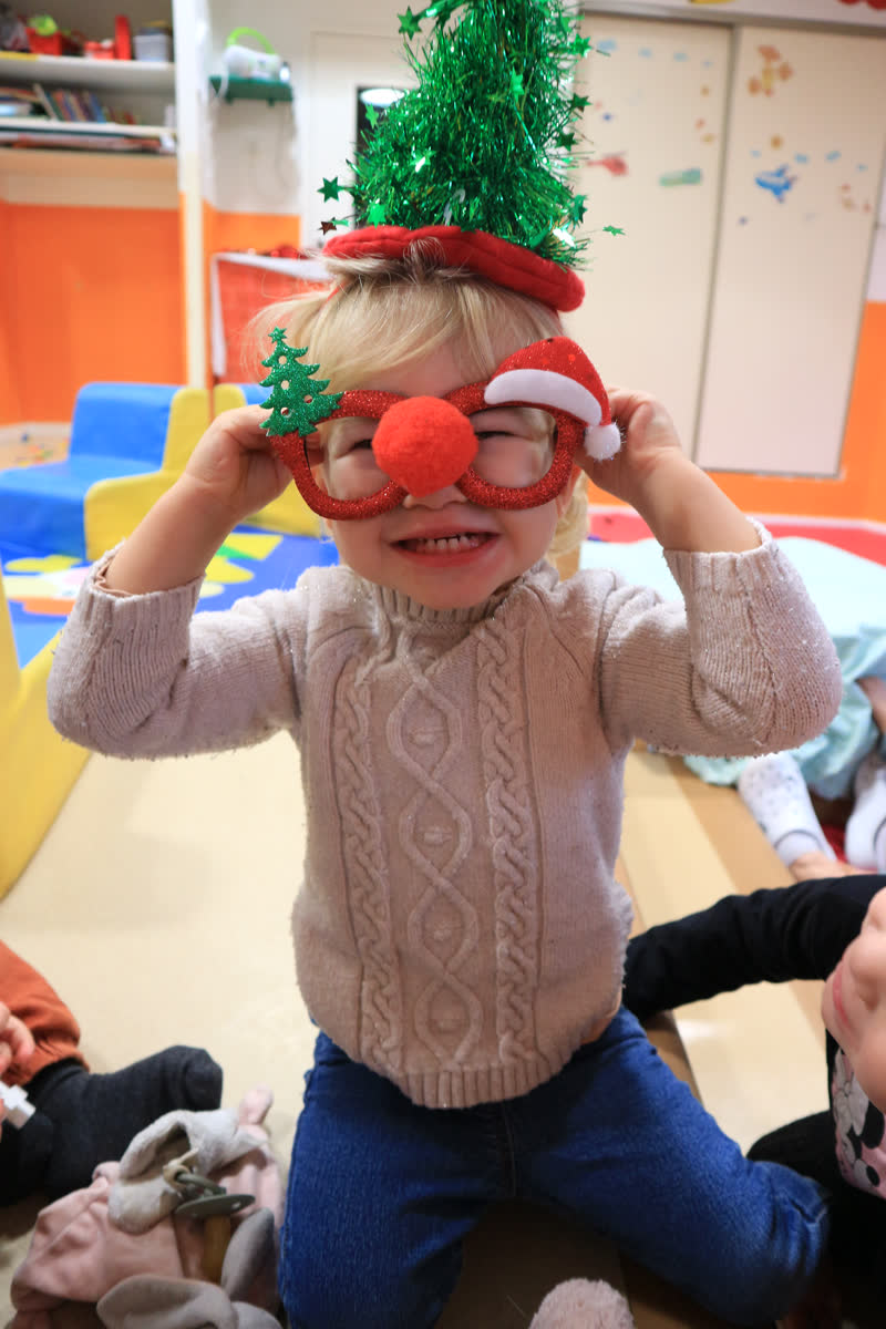 Un enfant porte des lunettes de Noël et un nez rouge